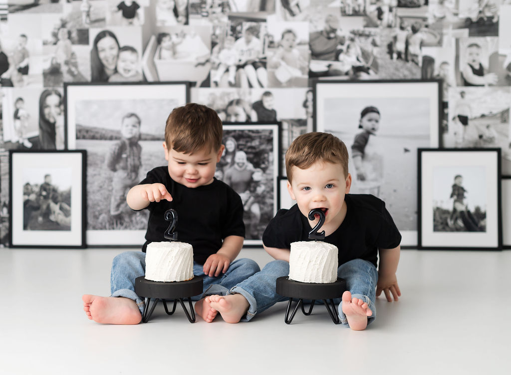 Boy eating candle during twin cake smash session with custom photo backdrop